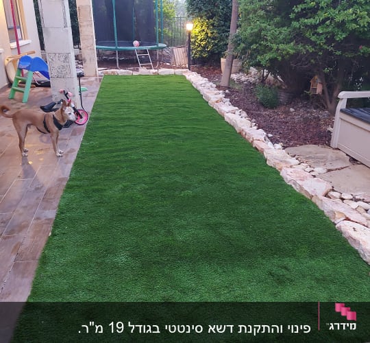 דשא סינתטי מוקף באבנים בגינה